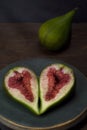 Sliced Ã¢â¬â¹Ã¢â¬â¹ripe figs in a round bronze aquamarine vintage plate on a wooden table under the rays of light. Royalty Free Stock Photo